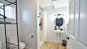 Une salle de bain équipée de toilettes, d’une douche, d’un lavabo et d’un miroir.