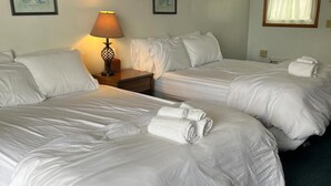 A hotel room with two beds, a nightstand with a lamp, and a window with curtains. - Double Room - 2 Queen Beds - Partial Lake View (Himrod)