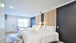 A modern hotel room with two beds, a large window, a wooden panel wall, and a blue and white patterned rug. - Double Room - 2 Queen Beds - Pool View (Himrod)