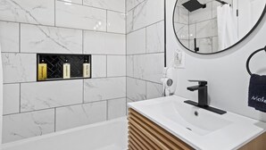 A modern bathroom with white marble tiles, a round mirror, a black faucet, and a wooden vanity. - Double Room - 2 Queen Beds - Lake View (Himrod)