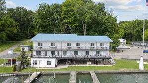 A multi-story hotel with a blue roof, located beside a body of water with docks. - Double Room - 2 Queen Beds - Lake View (Himrod)