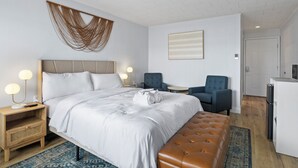 A hotel room with a large bed, a bench, a desk, a chair, and a kitchenette. - Single Room - 1 Queen Bed -Valley View (Himrod)