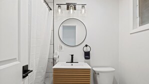 A bathroom with a white sink, a round mirror, a toilet, and a shower curtain. - Single Room - 1 Queen Bed -Valley View (Himrod)
