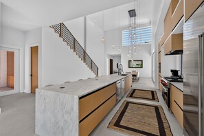 A modern kitchen with a central island, built-in appliances, and a staircase. - NEW Casa Tropicana Siesta Key Luxury Hot Tub Saltwater Pool Cabana Private Yard (Siesta Key)