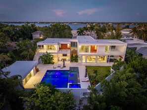A modern two-story house with a swimming pool, surrounded by lush greenery and a view of the sea. - NEW Casa Tropicana Siesta Key Luxury Hot Tub Saltwater Pool Cabana Private Yard (Siesta Key)