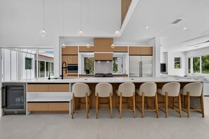 A modern kitchen with a central island, bar stools, and pendant lighting. - NEW Casa Tropicana Siesta Key Luxury Hot Tub Saltwater Pool Cabana Private Yard (Siesta Key)