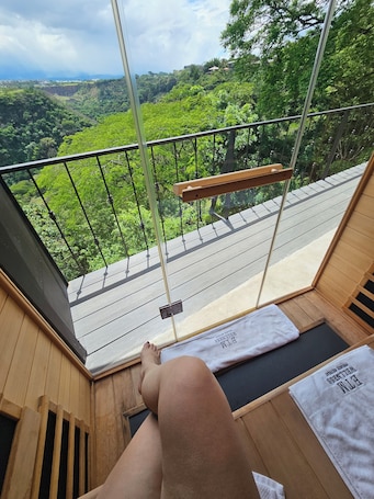 A wooden deck with a glass railing overlooking a lush green landscape.. Stay at ETM Wellness Private Retreat, an Oasis in San José just for you