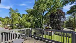 A balcony with a railing, a table, and two chairs. - Walk to Depot Town - Private Deck & King Bed (Ypsilanti)