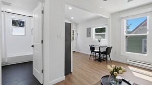 A modern interior with a dining area, a kitchen, and a bathroom. - Walk to Depot Town - Private Deck & King Bed (Ypsilanti)