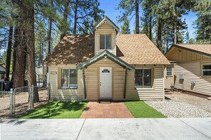 A single-story log cabin with a front door, a small porch, and a clear sky. - Big Bear 4 Seasons (Big Bear Lake)