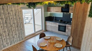 Une cuisine moderne avec des meubles en bois, une cuisinière à gaz et un coin repas comprenant une table ronde et des chaises.