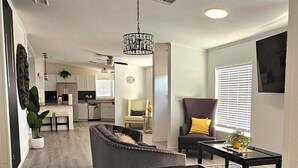 A modern living room with a sofa, coffee table, and armchair, a kitchen in the background, and a dining area with a table and chairs. - beautifly remodel home with spectacular mountain views 6 miles from the mall (Sierra Vista)