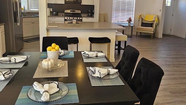A dining area with a large table, black upholstered chairs, a chandelier, and a kitchen in the background. - beautifly remodel home with spectacular mountain views 6 miles from the mall (Sierra Vista)