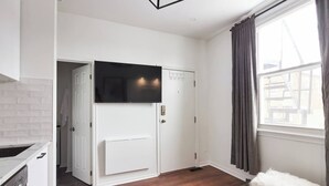 Eine moderne Küche mit weißen Schränken, einem eingebauten Backofen und einem großen Fenster mit Vorhängen.