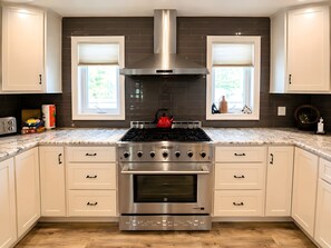 A kitchen with a stainless steel range, double oven, and a red kettle on the stove. - Spacious Family Retreat w/ Pool, Hot Tub, Fire Pit (Ligonier)