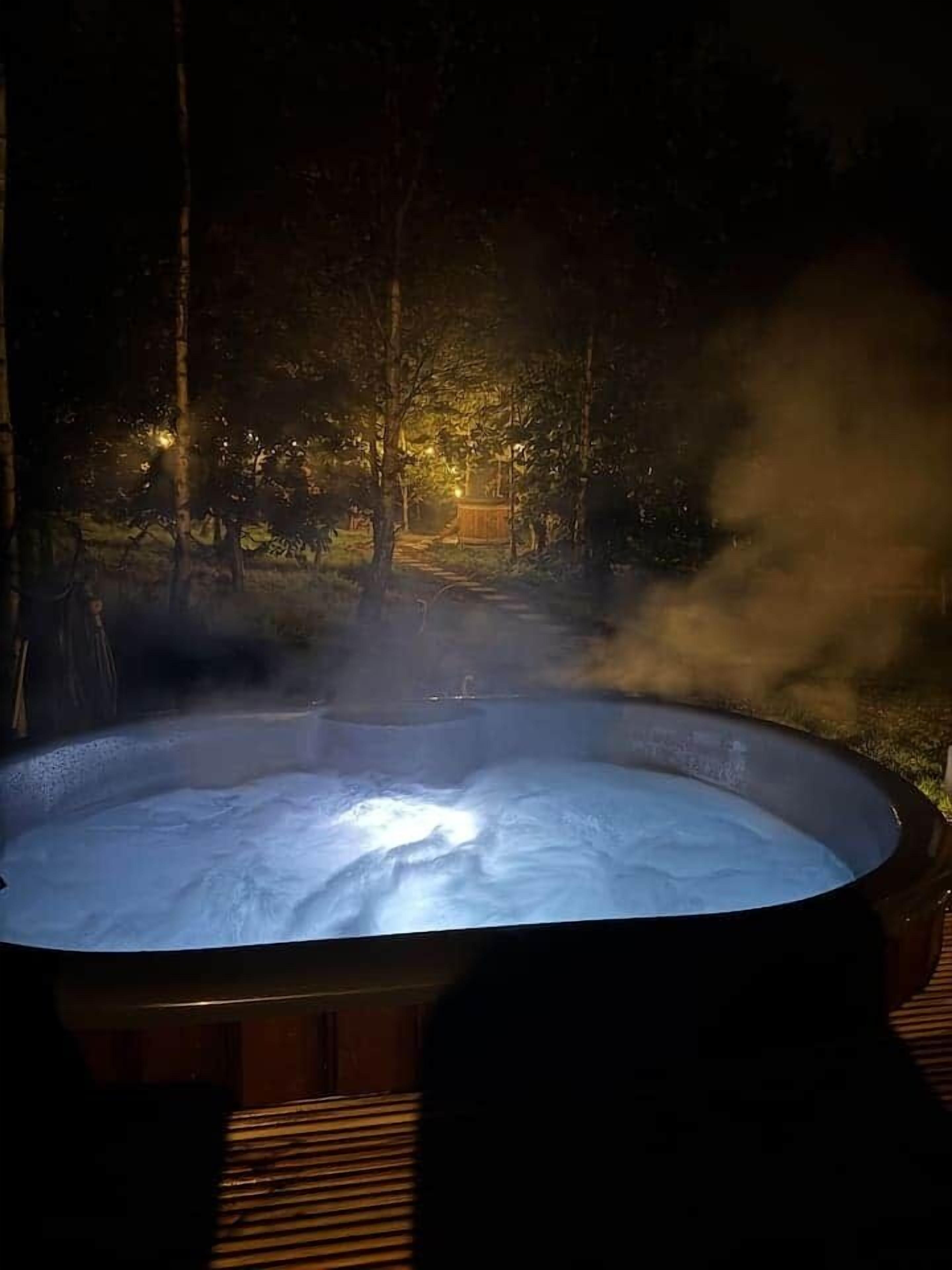 A hot tub in a forested area with steam rising from the water.