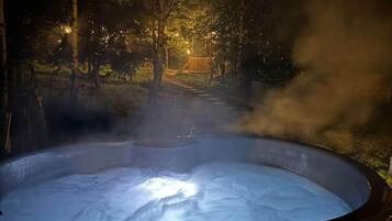 A hot tub in a forested area with steam rising from the water.