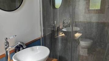 Une salle de bain avec un meuble-lavabo en bois, un lavabo blanc, un miroir, un espace douche et des toilettes.