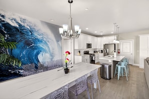 A modern kitchen with a large island, white cabinetry, and a wave-themed mural.