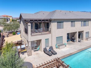 A two-story house with a pool, outdoor furniture, and a barbecue area.