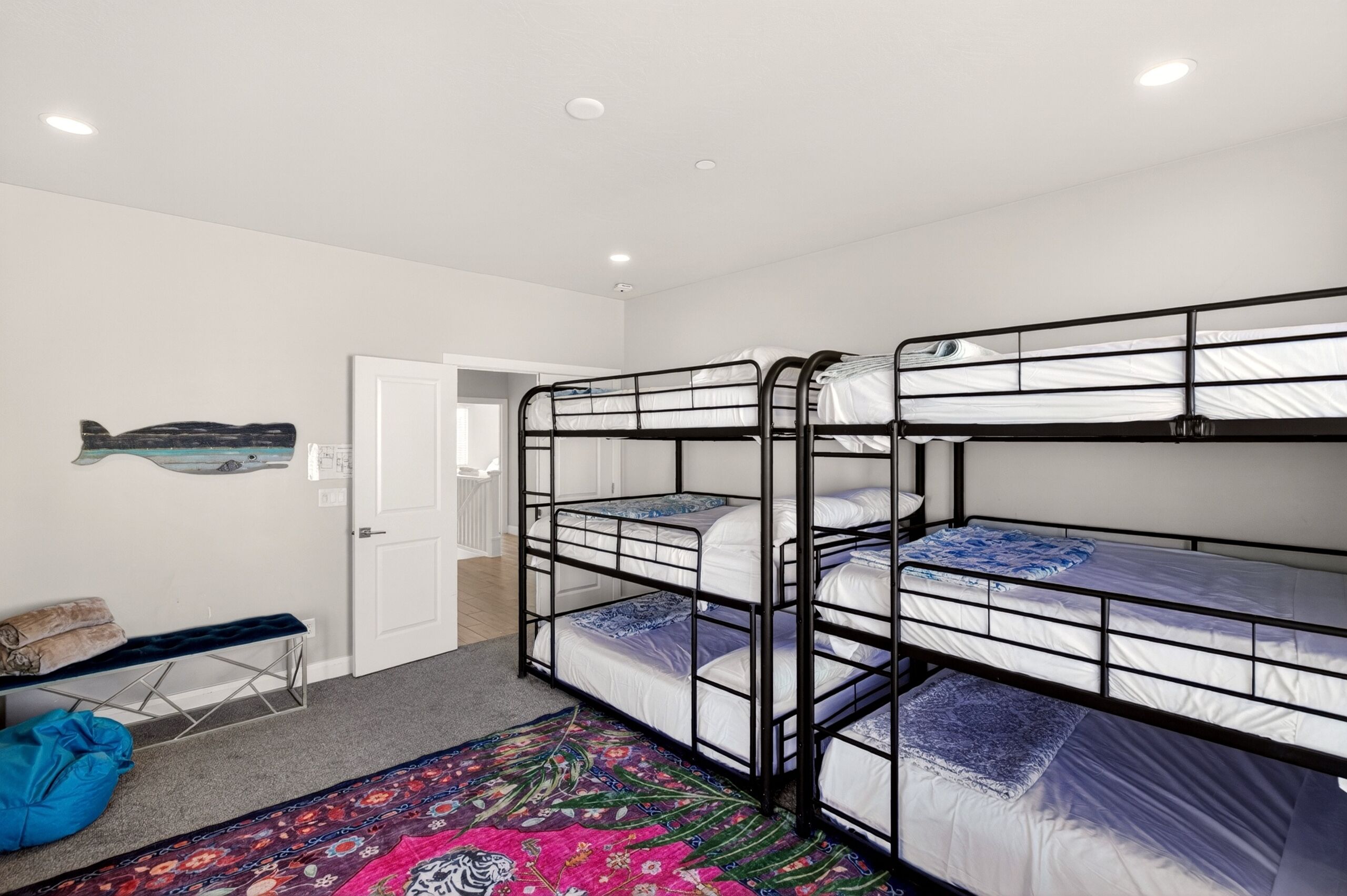 Ein Zimmer mit Etagenbetten, einer Bank, einer Tür und einer Fischdekoration an der Wand.