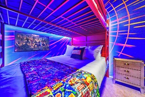 A bedroom with a bed, pillows, a wall-mounted TV, and a patterned bedspread. - New Resort Home, Pool and Spa, Game Room (Davenport)