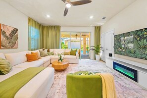 A modern living room with a sofa, coffee table, and TV. - New Resort Home, Pool and Spa, Game Room (Davenport)