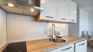 Una cocina moderna con estufa empotrada, lavaplatos de acero inoxidable y encimera de madera.