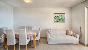 Una sala de estar con un sofá, sillas, una mesa de comedor y un cuadro en la pared.