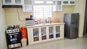 A kitchen with a gas stove, microwave, refrigerator, and cabinets.