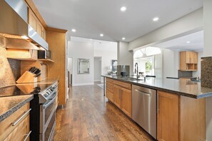 A modern kitchen with wooden cabinets, stainless steel appliances, and a granite countertop.