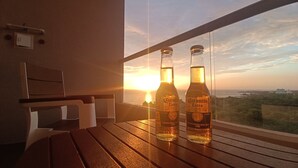 Two bottles of Corona Extra on a wooden table by a window with a sunset view. - Ideal for Resting! Apartasuite for Couples with Ocean View and Swimming Pools (Santa Marta)