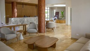 A spacious lobby with modern furniture, a central column, and a reception area. - Ideal for Resting! Apartasuite for Couples with Ocean View and Swimming Pools (Santa Marta)