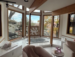 Ein modernes Badezimmer mit einer großen Badewanne, einem Handtuch und einem dekorativen Gegenstand auf einem kleinen Tisch.