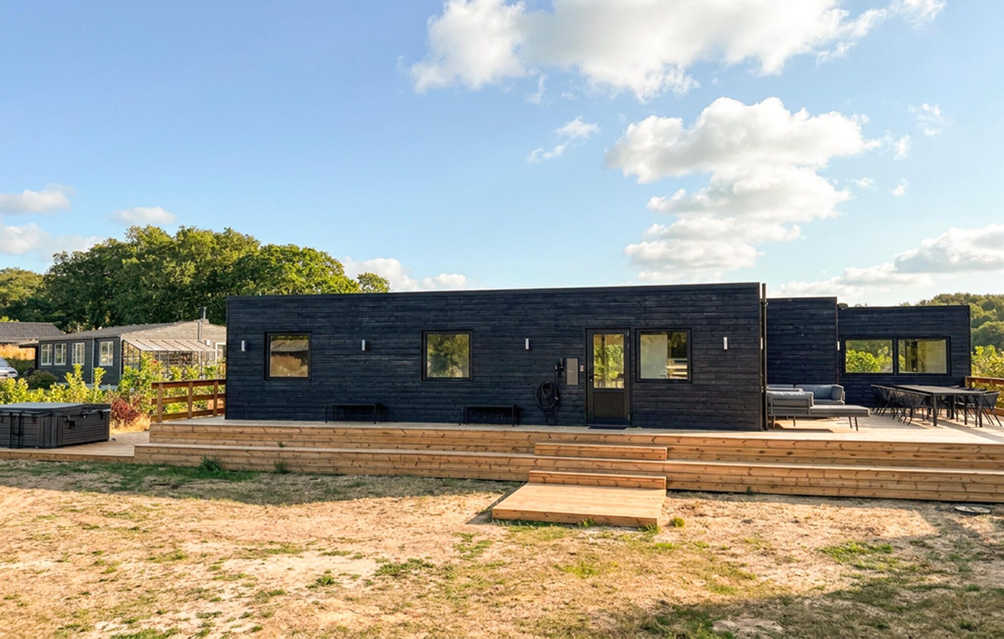 A modern two-story building with a flat roof, large windows, and a wooden deck in front.