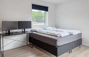A bedroom with a bed, a desk with two monitors, and a window with a view of greenery. - Awesome home in Ejstrupholm with sauna (Ejstrupholm)