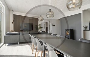 Ein modernes Wohnzimmer mit einer Couch, einem Esstisch und Pendelleuchten.