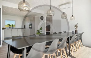 A modern kitchen with an oven, a dining area with a long table and chairs, and a view of the outdoors through a window. - Awesome home in Ejstrupholm with sauna (Ejstrupholm)