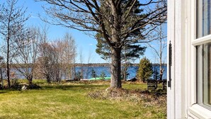 A grassy yard with a tree, a bench, and a view of a lake. - 4 Star Holiday Home in Vaxjo (Växjö)