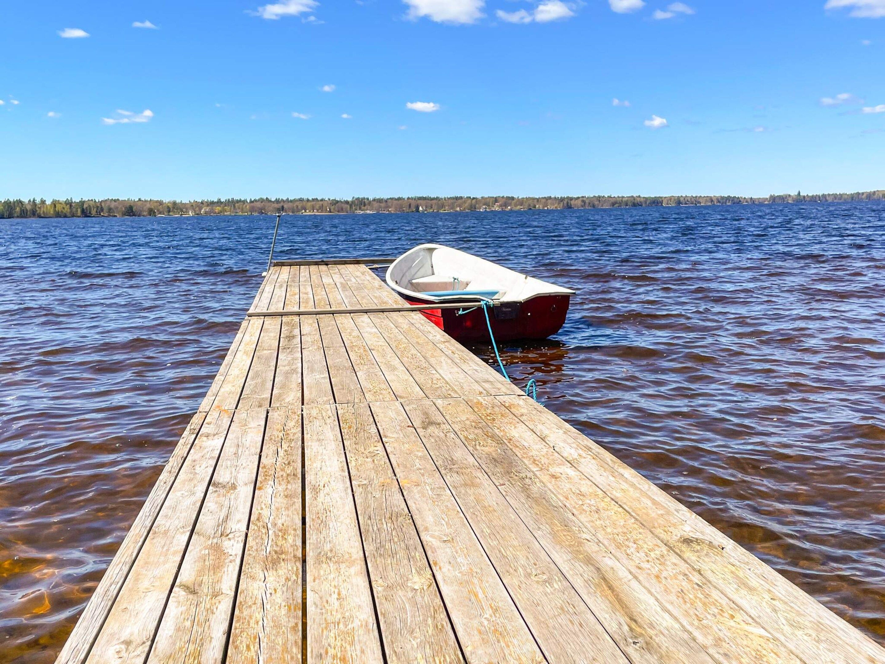 A wooden dock extending into calm water with a small boat tied to it.