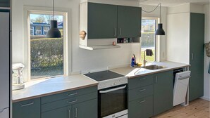 Una cocina moderna con horno integrado, lavavajillas y un amplio ventanal que proporciona luz natural.