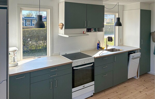 A modern kitchen with a built-in oven, a dishwasher, and a large window providing natural light. - 3 bedroom awesome home in Juelsminde (Juelsminde)