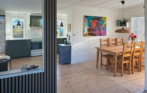 Une cuisine moderne avec un coin repas, un plancher en bois et une grande fenêtre.
