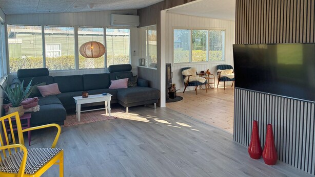 Una sala de estar moderna con un sofá, sillas, televisor y chimenea.