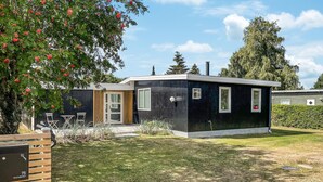 Una casa moderna de un piso con fachada oscura, puerta principal y un pequeño porche.