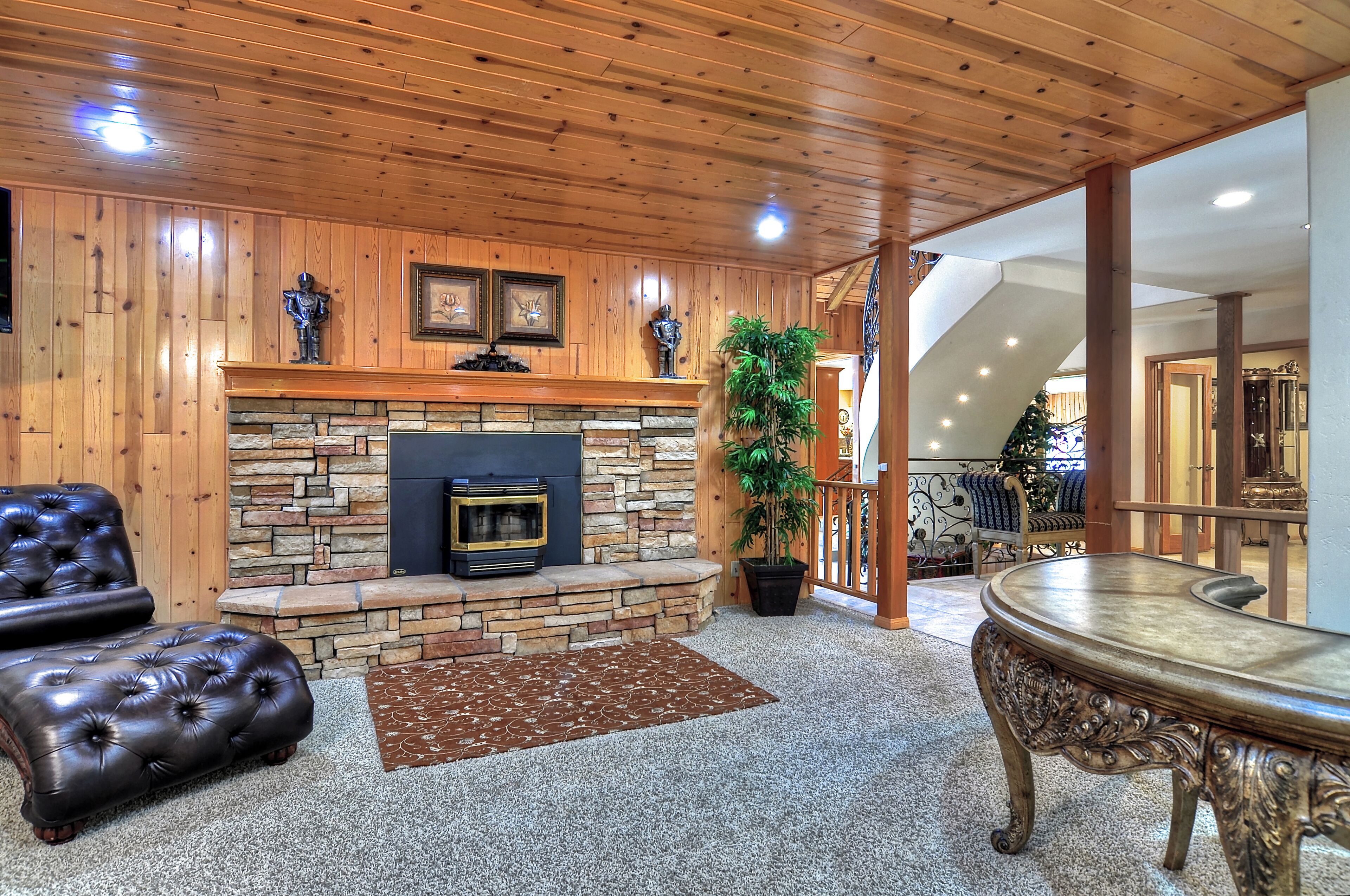 A cozy living room with a stone fireplace, leather sofa, and a dining table.