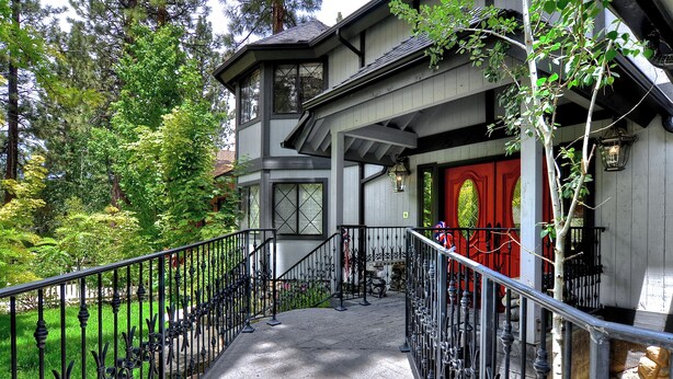 Ein Haus mit überdachter Veranda, einer roten Tür und einem steinbelagten Weg zum Eingang.