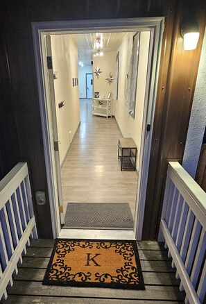A hallway leading to a room with a wooden floor, a bench, and a star decoration on the wall. - The Katherine (Troy)