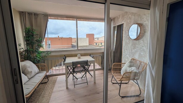 A balcony with a table, chairs, a sofa, and a potted plant. - T2 Bis Swimming pool and sea view (Agde)