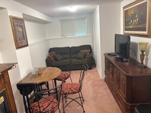 Ein Wohnzimmer mit einer Couch, einem Fernseher und einem Esstisch mit Stühlen.